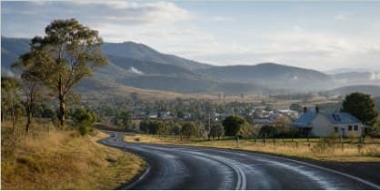 A country road curving toward a small town below distant ranges.